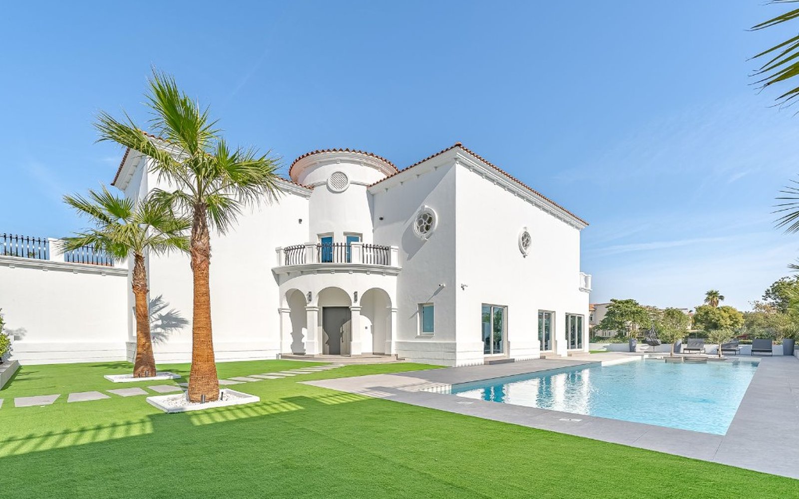 Luxury white Mediterranean villa with swimming pool, palm trees, and manicured lawn